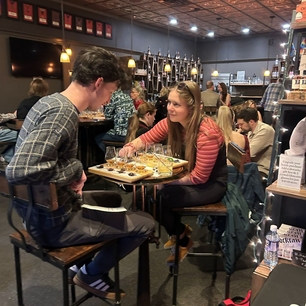 People sitting at a bar with drinks and food on a tray