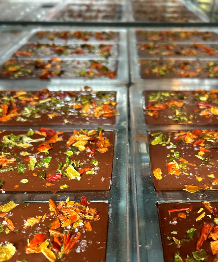 Chocolate bars with pueblo chile toppings getting ready to be packaged.