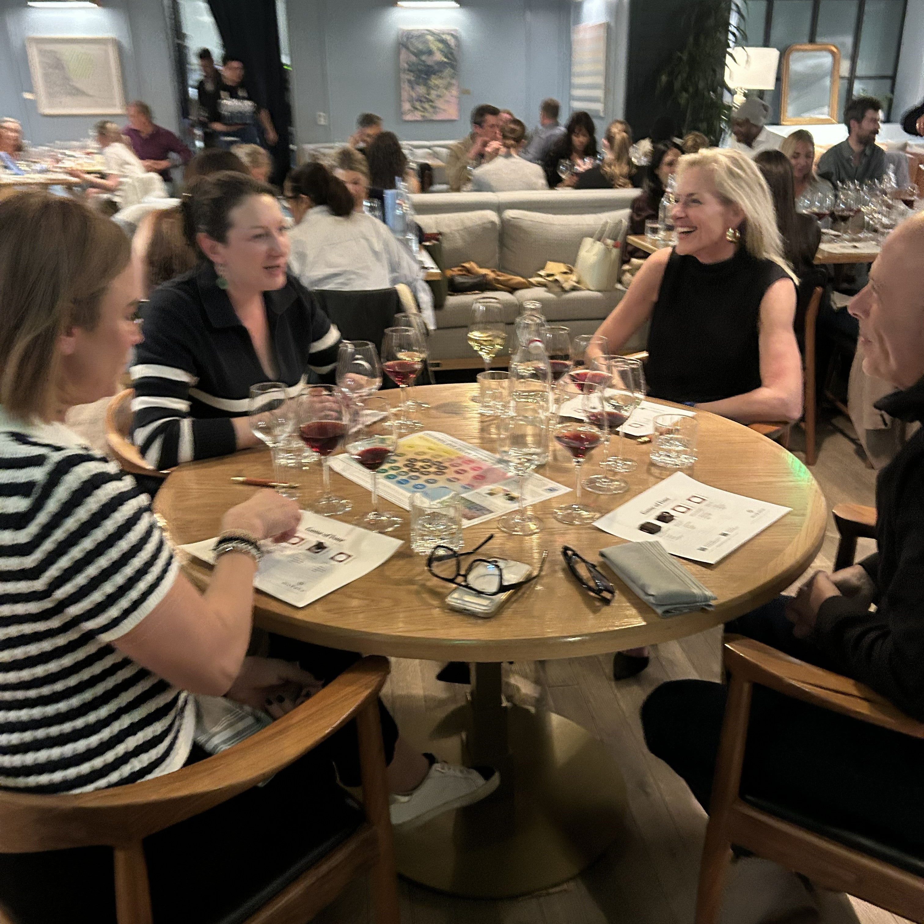 People sitting around a table in a restaurant setting with drinks and artwork.