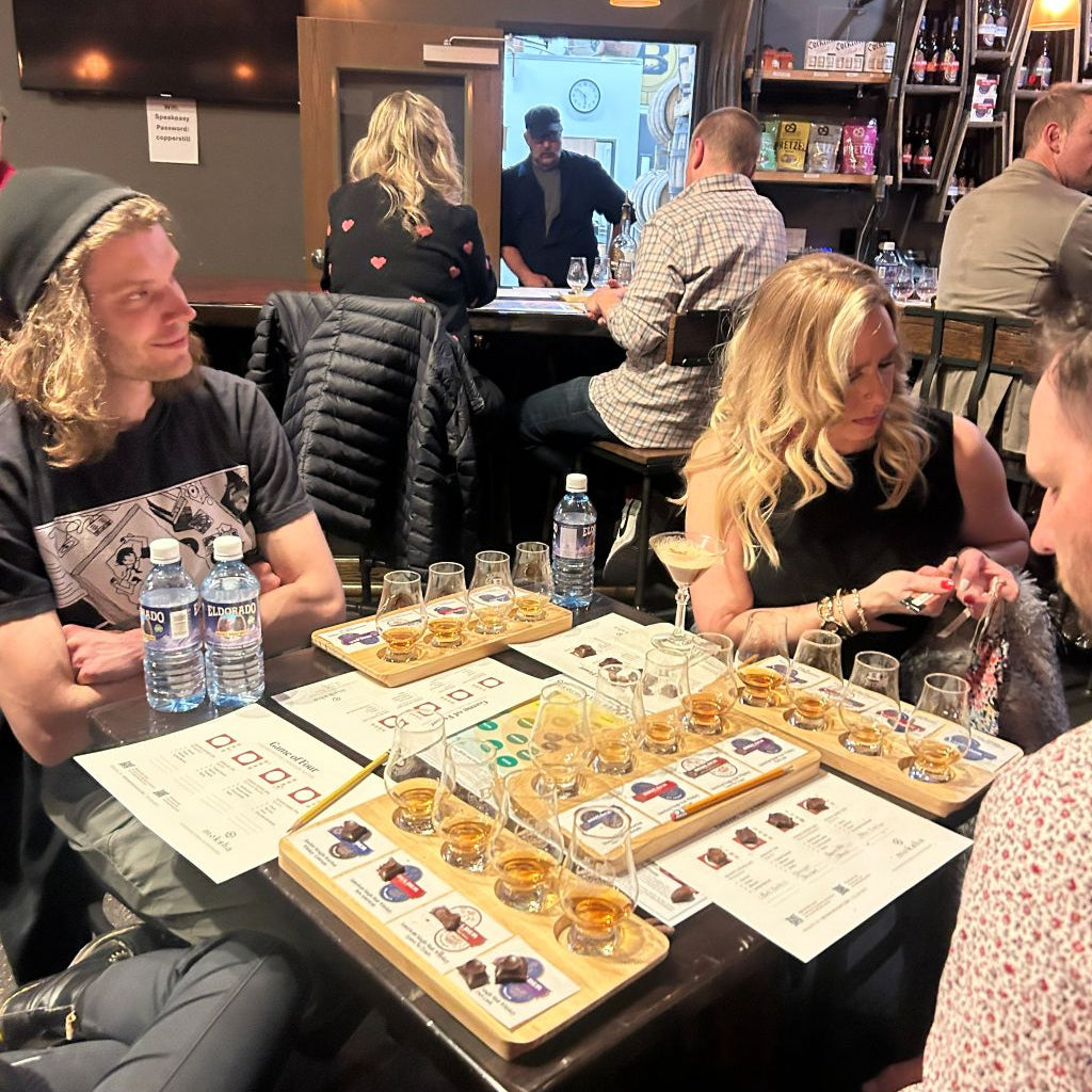 Group of people sitting around a table with board games and drinks in a casual setting.