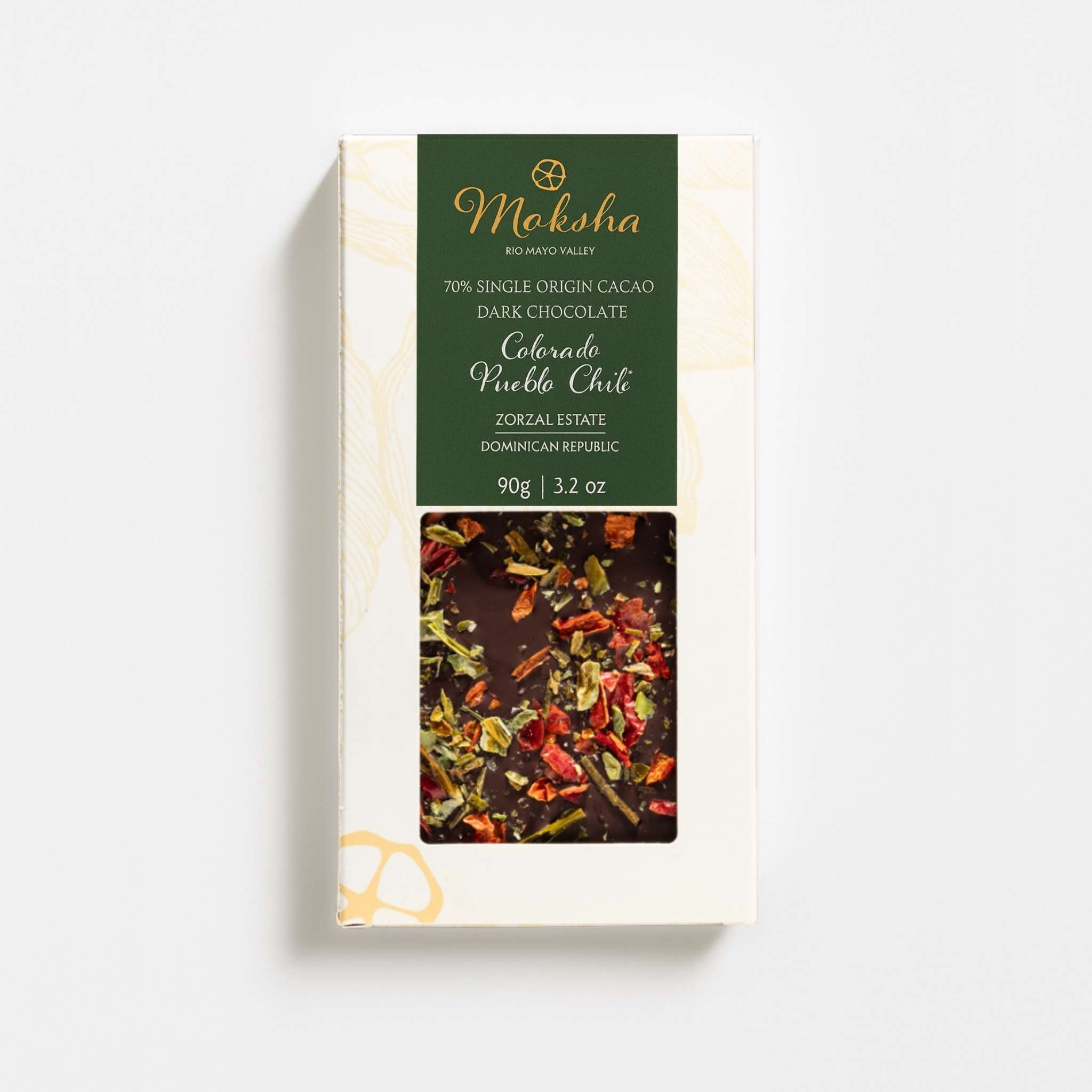 Moksha Colorado Pueblo Chile dark chocolate bar in cream and green packaging, shown on a white background with soft, diffused shadows.