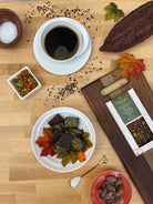 Cocoa-themed table setting with a cup of coffee, Pueble Chile chocolate, and fall decorations on a wooden surface.