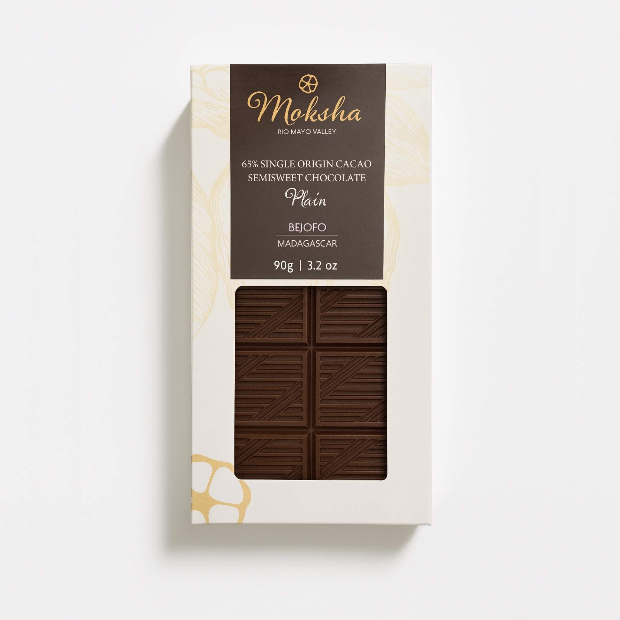 Moksha 65% single origin semisweet chocolate bar from Bejofo, Madagascar, in white packaging with a dark brown label and a window revealing the chocolate bar.