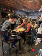 People sitting at a bar with drinks and food on a tray