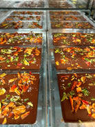 Chocolate bars with pueblo chile toppings getting ready to be packaged.