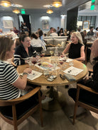People sitting around a table in a restaurant setting with drinks and artwork.