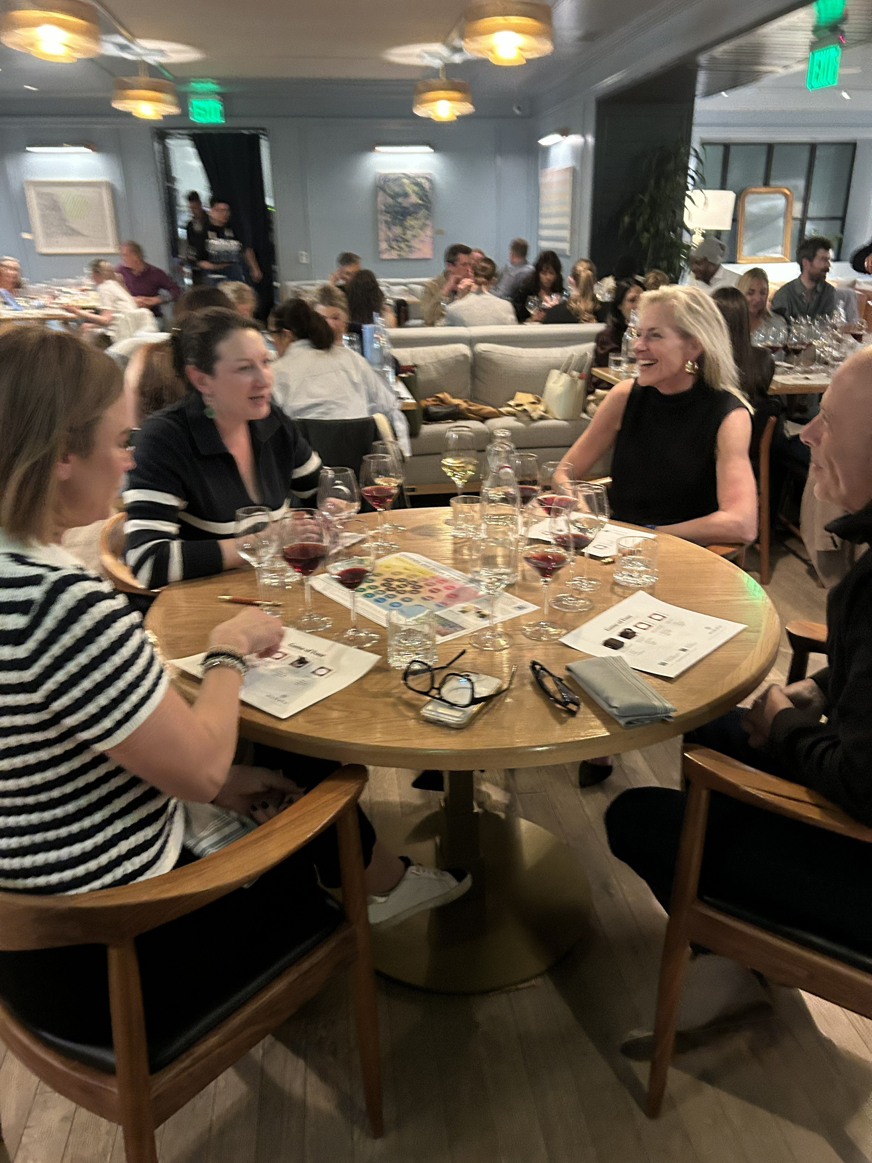 People sitting around a table in a restaurant setting with drinks and artwork.