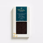 Moksha's 70% Iténez Wild Harvest dark chocolate bar in white and gold packaging with a deep teal label and a window showing the patterned dark chocolate.