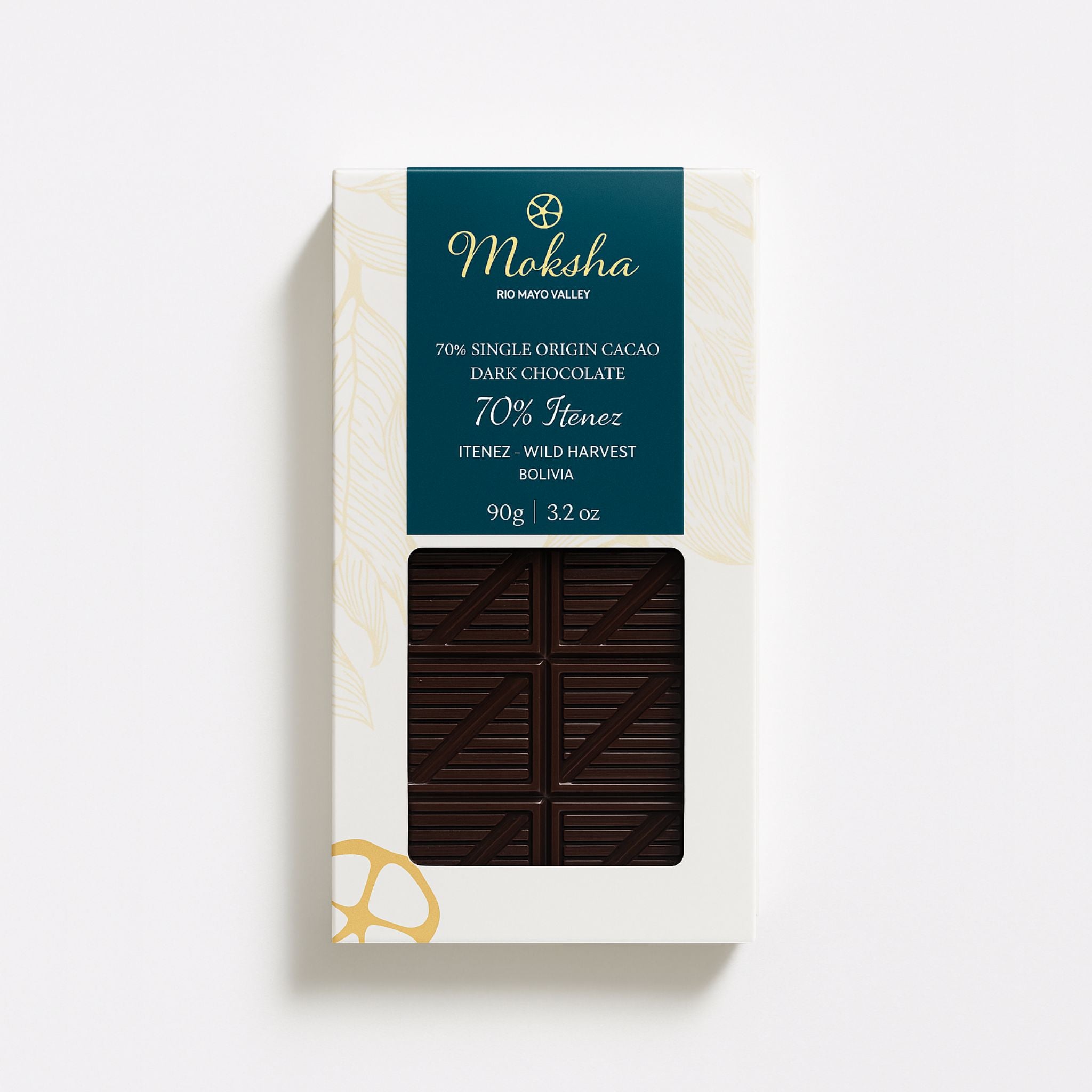 Moksha's 70% Iténez Wild Harvest dark chocolate bar in white and gold packaging with a deep teal label and a window showing the patterned dark chocolate.