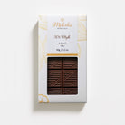 Moksha 50% Vegan Mylk chocolate bar in white and gold packaging with a clear window showing the patterned milk-style chocolate.