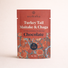 Moksha Turkey Tail Maitake & Chaga functional mushroom chocolate pouch, 70% dark vegan chocolate, daytime blend packaging on a light neutral background.
