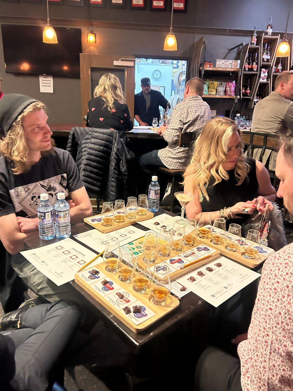 Group of people sitting around a table with board games and drinks in a casual setting.