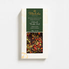 Moksha Colorado Pueblo Chile dark chocolate bar in cream and green packaging, shown on a white background with soft, diffused shadows.